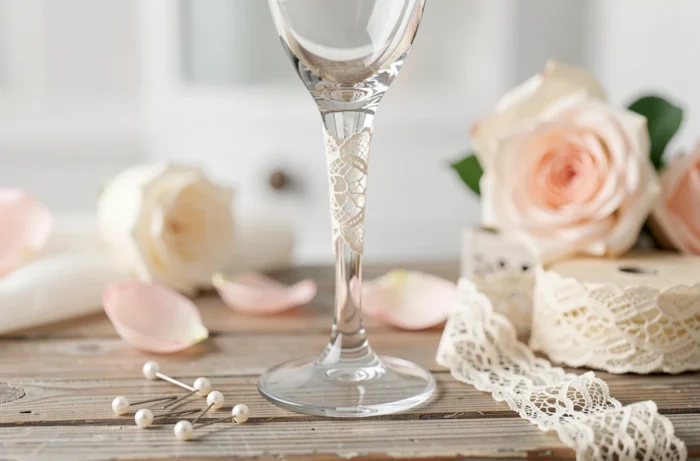 Flûte à champagne avec une bande de dentelle ivoire délicate collée autour du pied, posée sur une surface en bois vintage