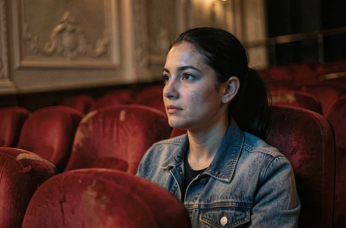 Femme absorbée par un film dans une salle de cinéma indépendante aux fauteuils en velours rouge