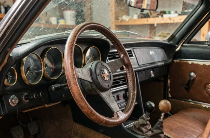 Tableau de bord et volant d'une Alfa Romeo Spider 1970 en cuir vieilli, détail intérieur vintage